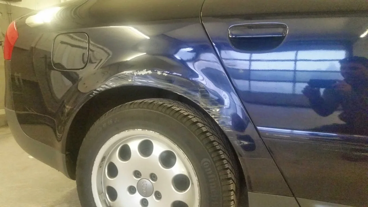 Beschädigter blauer hinterer Radlauf mit sichtbaren Verformungen und Lackspuren