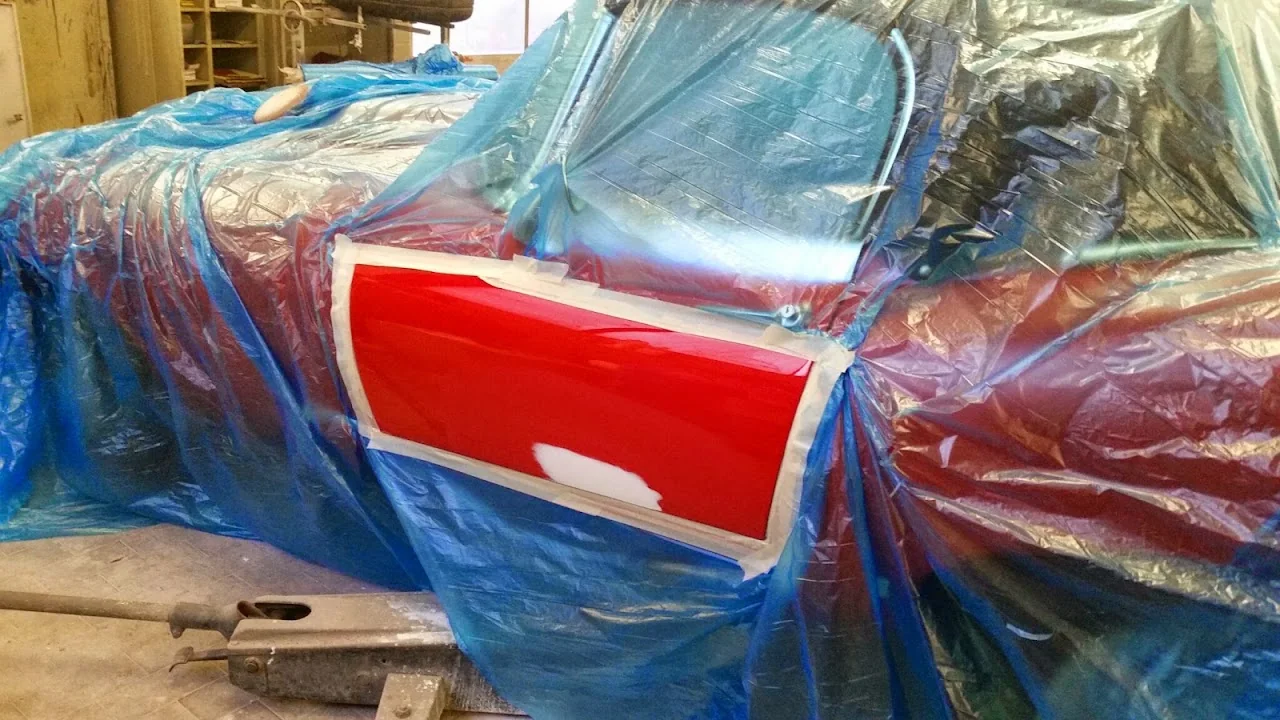 Rote Fahrzeugtür mit lokal vorbereiteter Reparaturstelle und abgedeckten Nachbarflächen